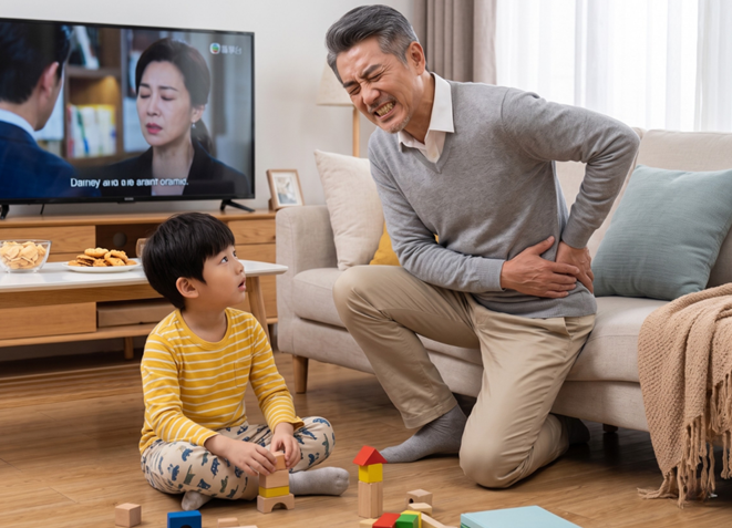 爺爺因「髖關節痛」而表情極度痛苦，半跪在沙發旁並右手按著他的髖部 